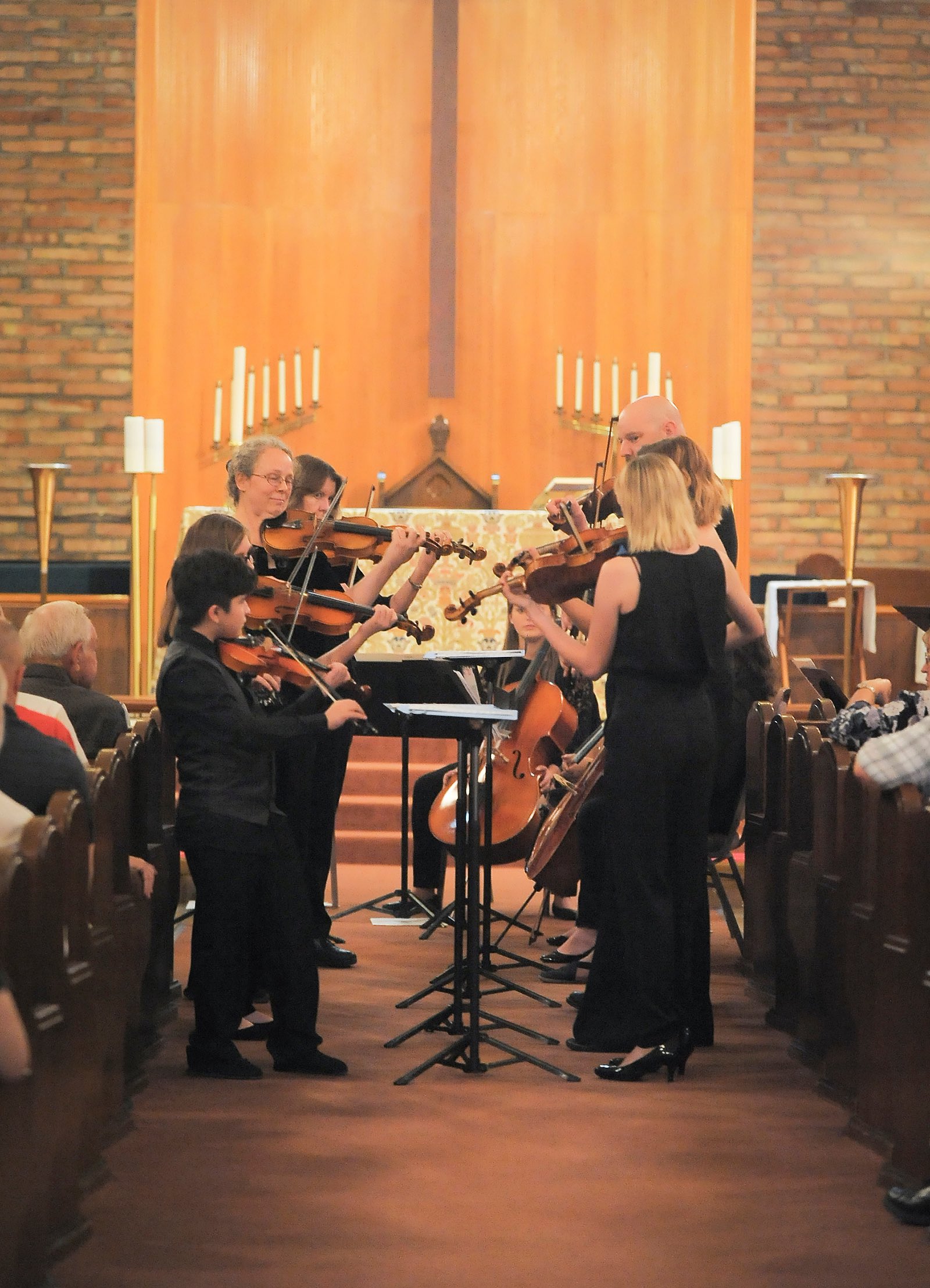 Performers stand playing string instruments in a church