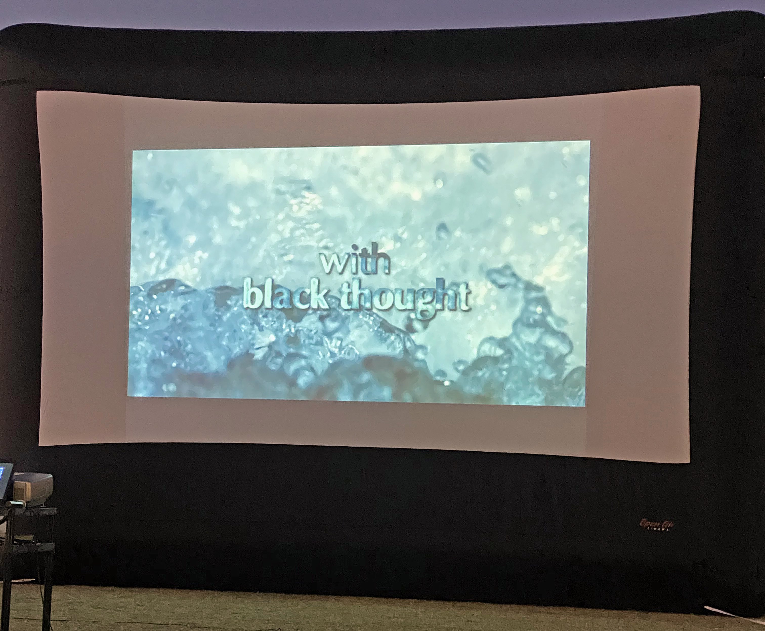 a projection screen shows a watery background with the words "With black thought"