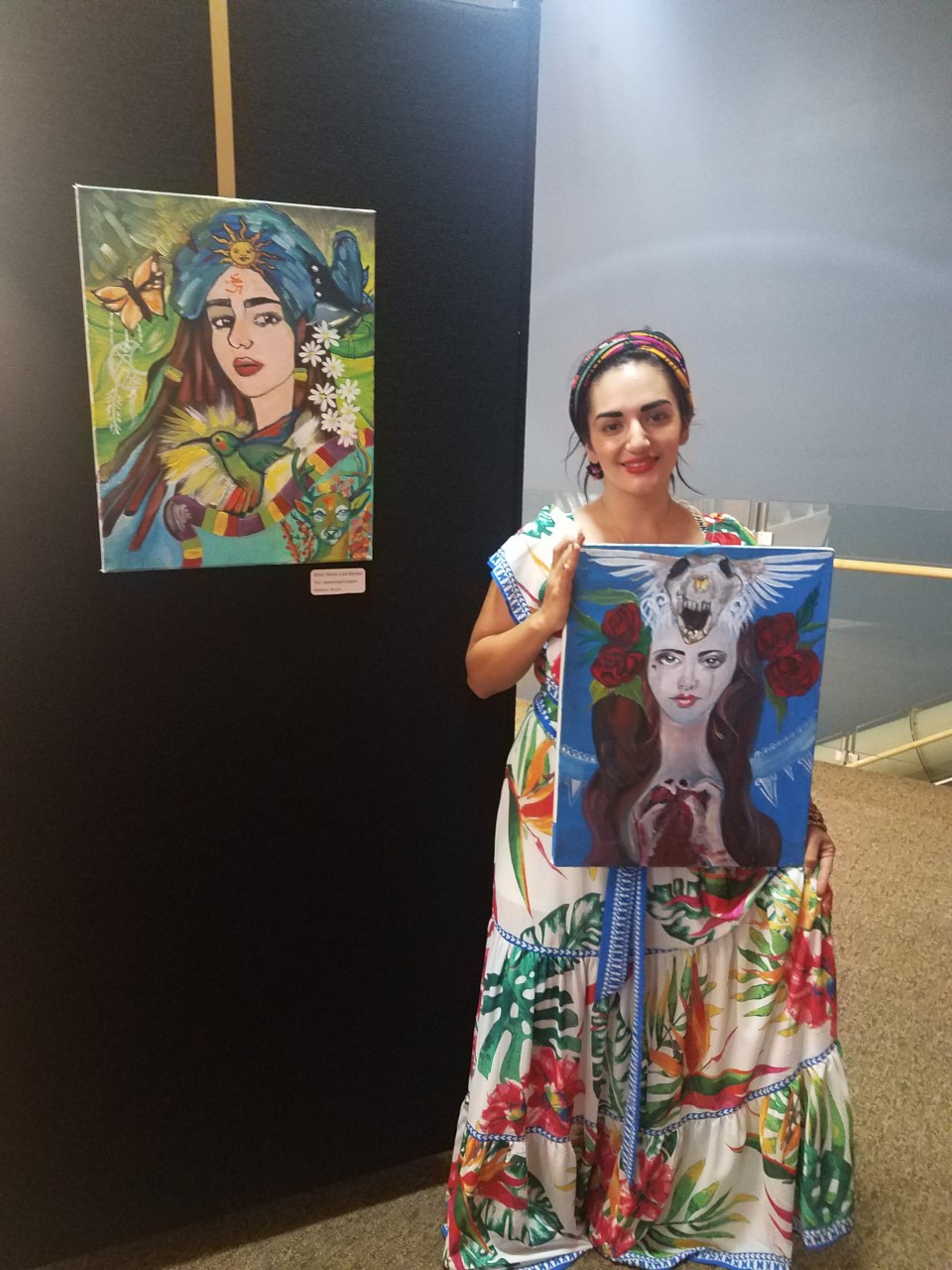 A woman dressed like Frida Kahlo holding up a painting by another painting.