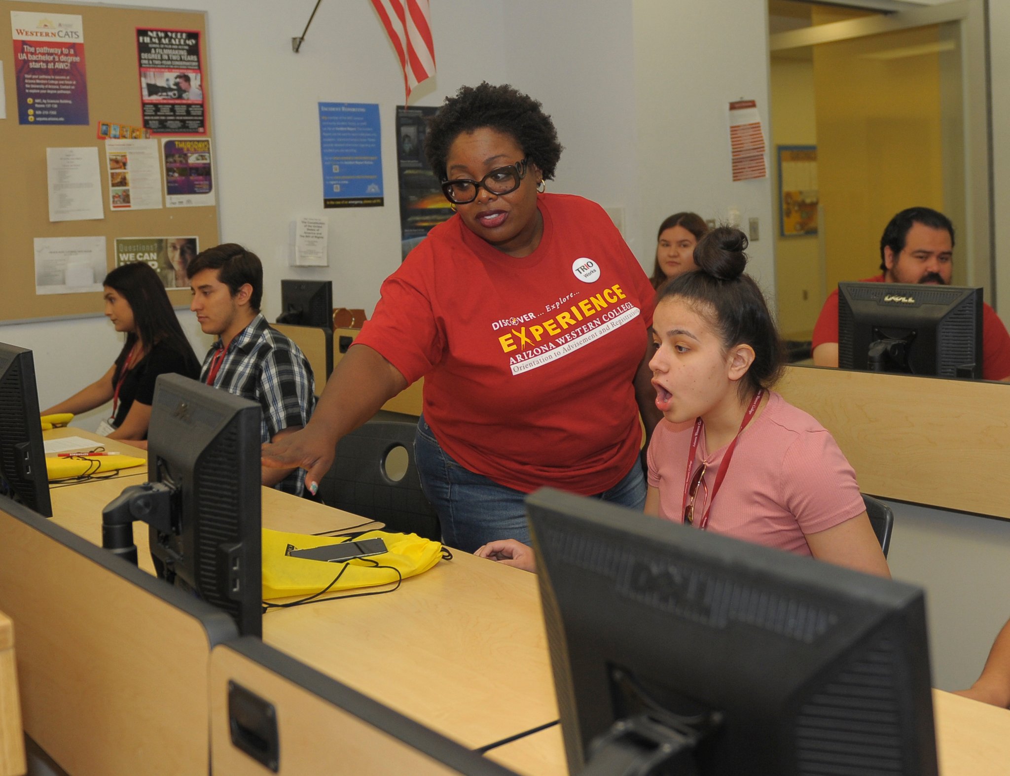 African-American woman points to a computer screen as she helps a student.