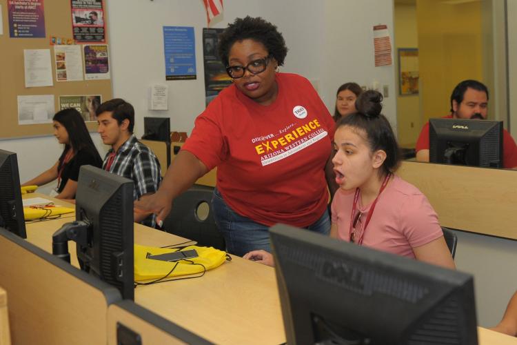 African-American woman points to a computer screen as she helps a student.