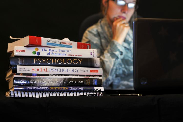 college books in front of a soldier looking into a computer.