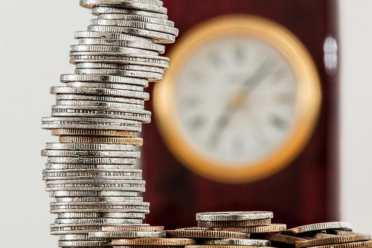 Quarters are stacked in an imperfect column with a gold-accented clock blurred in the background