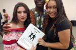 two women and a man pose with a salsa dance booklet